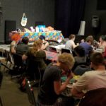 crowd shot of people sitting at tables in a dark room playing bingo